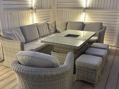 A corner seating area with cushioned chairs and stools around a glass topped table at Ty Coed in Abersoch