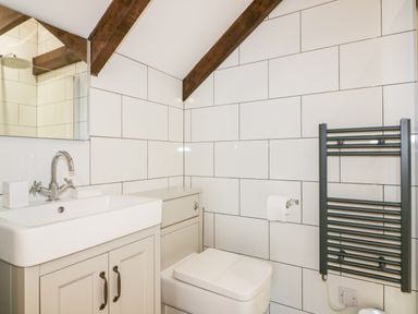 A bathroom with a sink cabinet toilet and towel rail at Beacon Barn in St Agnes