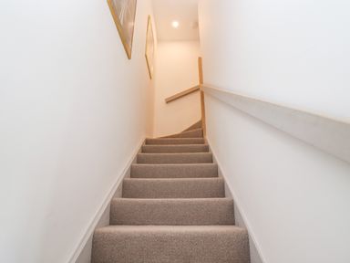 A carpeted staircase with handrails on both sides and framed pictures on the wall at Stow Cottage Barn in Churchill Oxfordshire