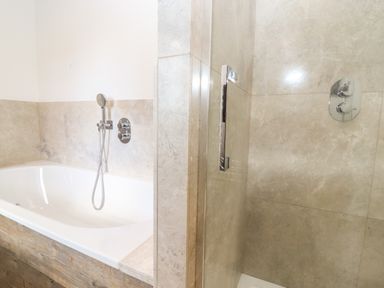 A bathroom with a bathtub and a separate shower area at Stow Cottage Barn in Churchill Oxfordshire