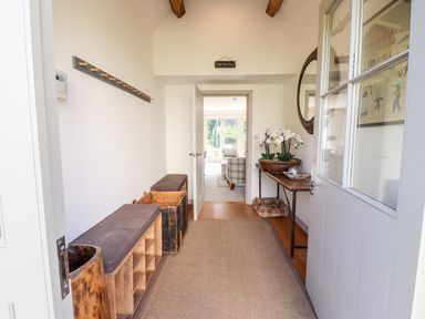 A hallway with benches shoe storage and a table with flowers at Stow Cottage Barn in Churchill Oxfordshire