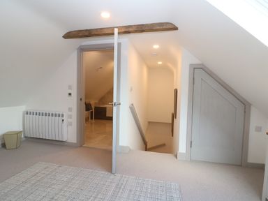 A hallway with an open door leading to a bathroom and stairs going down at Stow Cottage Barn in Churchill Oxfordshire