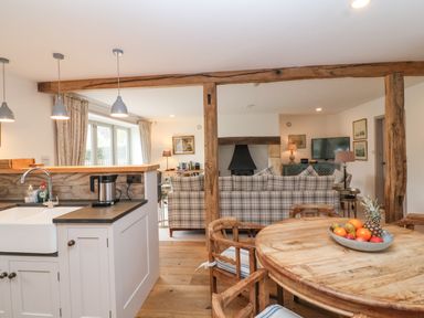 A kitchen and living area with a table of fruit and plaid sofas at Stow Cottage Barn in Churchill Oxfordshire