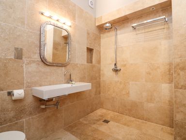 A bathroom with a wall-mounted sink mirror shower and toilet paper holder at Landmark in Salcombe