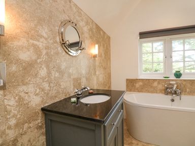A bathroom with a sink vanity and a bathtub under a window at Landmark in Salcombe