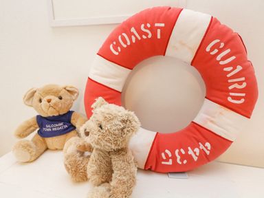 Two teddy bears with a red and white coast guard life ring on a table