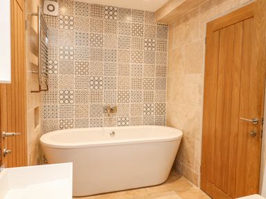 A bathroom with a freestanding bathtub and patterned wall tiles at Landmark in Salcombe