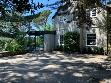 An exterior view of a two story house with multiple windows and surrounding trees at Landmark in Salcombe