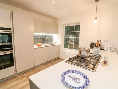 A kitchen with white cabinets a gas stove a sink and a window at Landmark in Salcombe