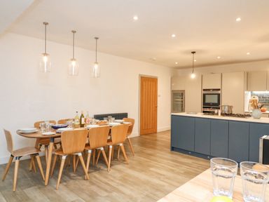 A kitchen with a dining table set with bottles and plates beside a kitchen island at Landmark in Salcombe