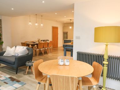 A dining area with a round table and four chairs with mugs on the table a yellow floor lamp and a radiator at Landmark in Salcombe