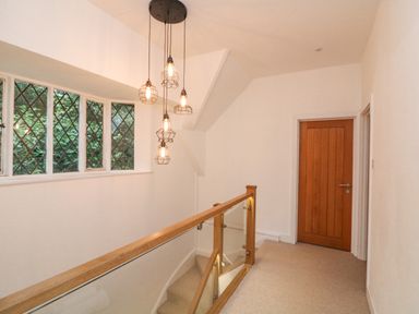 A stairway landing with wooden door and hanging pendant lights at Landmark in Salcombe