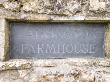 A stone plaque engraved with Lackington Farmhouse embedded in a stone wall at The Coach House at Lackington Farm in Piddletrenthide