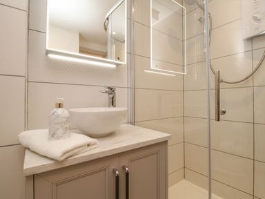 A bathroom with a shower area a round sink on a countertop and a towel with soap at The Coach House at Lackington Farm in Piddletrenthide