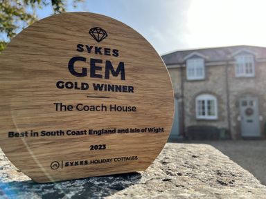 A wooden award on a stone surface with a house in the background at The Coach House at Lackington Farm in Piddletrenthide