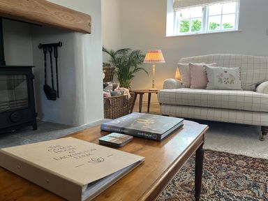 A living room with a checked sofa cushions on a wooden coffee table next to a fireplace at The Coach House at Lackington Farm in Piddletrenthide