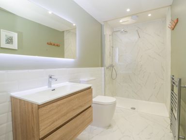 A bathroom with a wooden vanity sink a toilet a large mirror and a walk in shower at The Shippon in Honiton