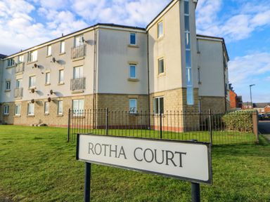 A lawn in front of a multi-story residential building with balconies and satellite dishes at Rotha Court