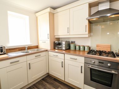 A kitchen with cream cabinets a double sink a toaster canisters a toaster oven and a gas stove at Sandy Corner in Blyth Northumberland