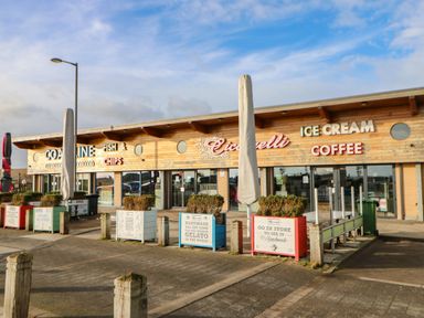 An outdoor view of a food building with signs for fish and chips ice cream and coffee at Sandy Corner in Blyth Northumberland