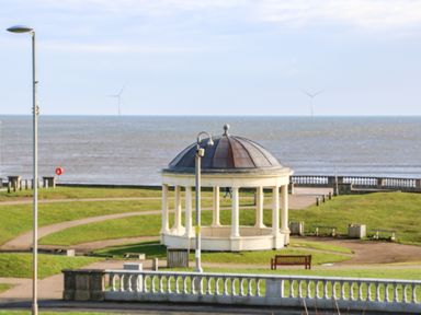 A park with a pavilion near the sea and wind turbines in the background at Sandy Corner in Blyth Northumberland