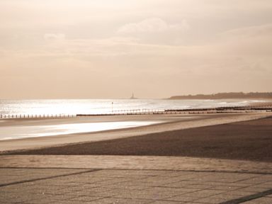 A beach with a paved walkway and breakwaters along the shore at Sandy Corner in Blyth Northumberland