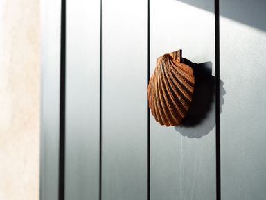 A close up of a brown shell shaped door knocker on a gray door at Church Rooms in Port Isaac