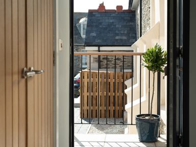 A small balcony with a potted plant and a metal railing outside a door at Church Rooms in Port Isaac
