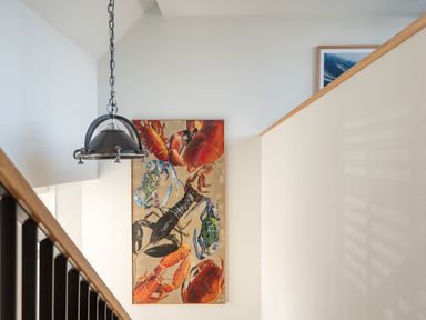 A staircase with a hanging light fixture and a painting of lobsters and crabs on the wall at Church Rooms in Port Isaac