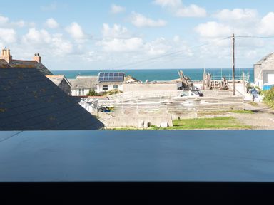 A view of rooftops with solar panels and construction materials near the ocean at Church Rooms in Port Isaac