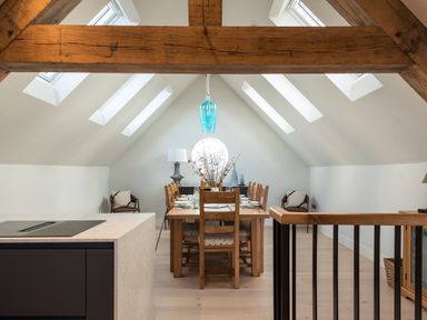 A dining area with a wooden table and chairs under skylights in an attic space at Church Rooms in Port Isaac