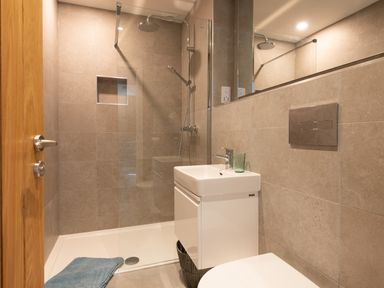 A bathroom with a walk in shower a white sink with a green glass and a toilet at Church Rooms in Port Isaac
