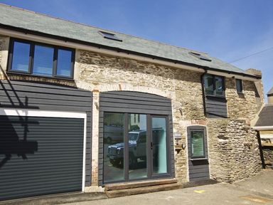Stone building with black doors and windows under a sloped roof at The Barn 20 At The Beach in Torcross