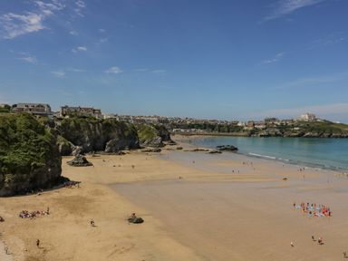 A sandy beach with people near cliffs and houses overlooking the sea at 13 Cliff Edge in Newquay