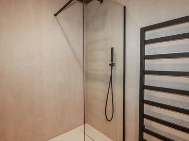 A shower with glass panel and towel radiator at 13 Cliff Edge in Newquay