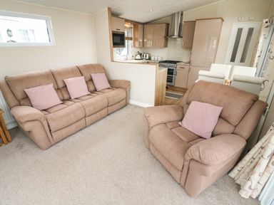 A living room with two sofas and a view into a kitchen at Yealands 27 South Lakeland Leisure Village near Carnforth