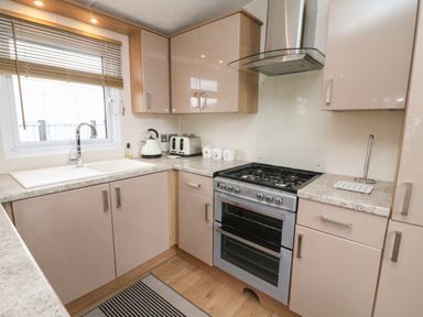 A kitchen with a gas stove sink toaster kettle and cabinets at Yealands 27 South Lakeland Leisure Village near Carnforth