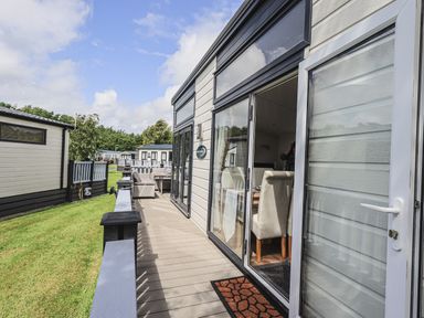 An outdoor deck area with seating and dining furniture attached to a mobile home at Yealands 27 South Lakeland Leisure Village near Carnforth