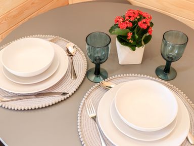 A round dining table with two place settings and a small plant in a white pot at Sea View in St Buryan