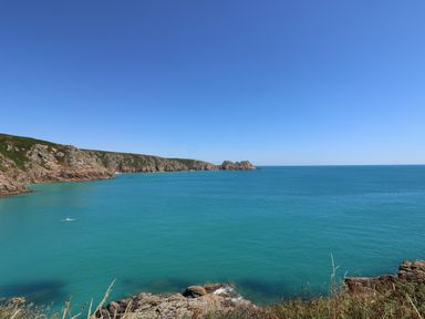 A coastal landscape with rocky cliffs and blue sea under a clear sky at Sea View in St Buryan