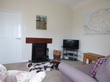 A living room with a fireplace a television on a stand and a sofa at Hafod Cottage in Cemaes Bay