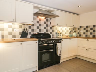 A kitchen with white cabinets a black oven wooden countertops and a checkered tile backsplash at Brookside in Grizebeck