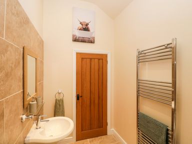 A bathroom with a sink mirror wooden door towel ring and a chrome towel radiator at Brookside in Grizebeck