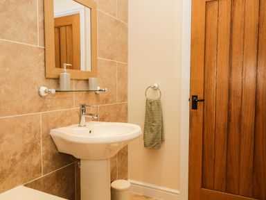 A bathroom sink with a mirror above and a wooden door beside at Brookside in Grizebeck