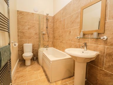A bathroom with a toilet bathtub with shower sink and mirror at Brookside in Grizebeck