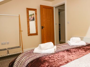 A bedroom with bed folded towels wooden door wall mirror and storage baskets at Brookside in Grizebeck