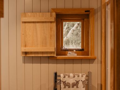 A small wooden window with a shutter open and a towel hanging on a rack below at Llethr - Shepherds Hut in Llanbedr