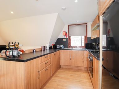 A kitchen with wooden cabinets black countertops and appliances at Owl Lodge in South Laggan near Invergarry