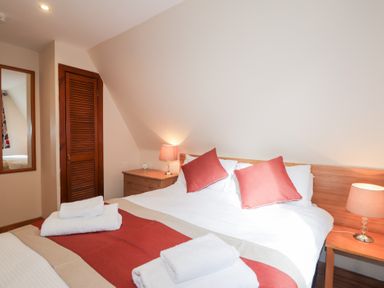 A bedroom with a double bed two bedside tables lamps and folded towels at Owl Lodge South Laggan near Invergarry