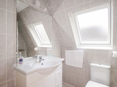 A bathroom with a sink cabinet mirror window toilet and towel at Owl Lodge South Laggan near Invergarry